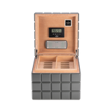 The Colibri Heritage Cube Humidor features a square gray design, cedar wood interior, digital hygrometer and humidifier on the inside lid, and two compartments for cigar storage.