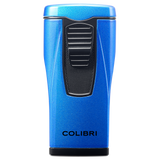 A metallic blue Colibri Monaco lighter with triple-jet flames and a black ignition trigger, featuring the brand name Colibri near the base, is displayed against a white background.